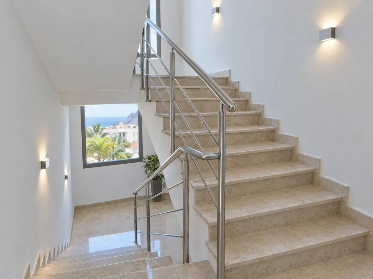 Escalera comunitaria reformada con peldaños de piedra, pasamanos de acero e iluminación LED