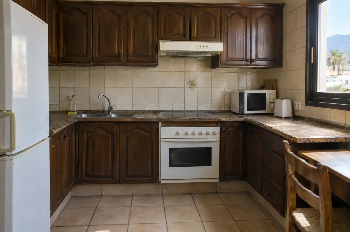Cocina de un piso en Tenerife antes de la reforma: muebles de madera oscura y azulejo beige
